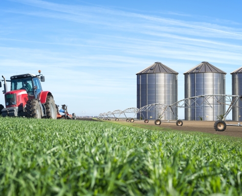 Agriculture and food production concept with tractor machine silos and irrigation system.